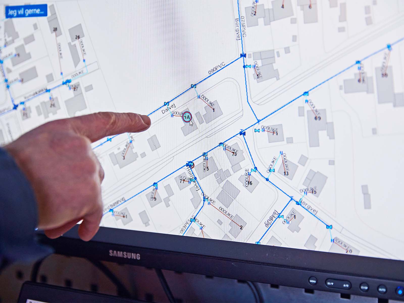 Finger peger på stophane for vand på et kort på en computerskærm